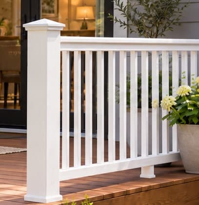 White deck railing with square posts, vertical balusters and top and bottom rails on a brown wood deck