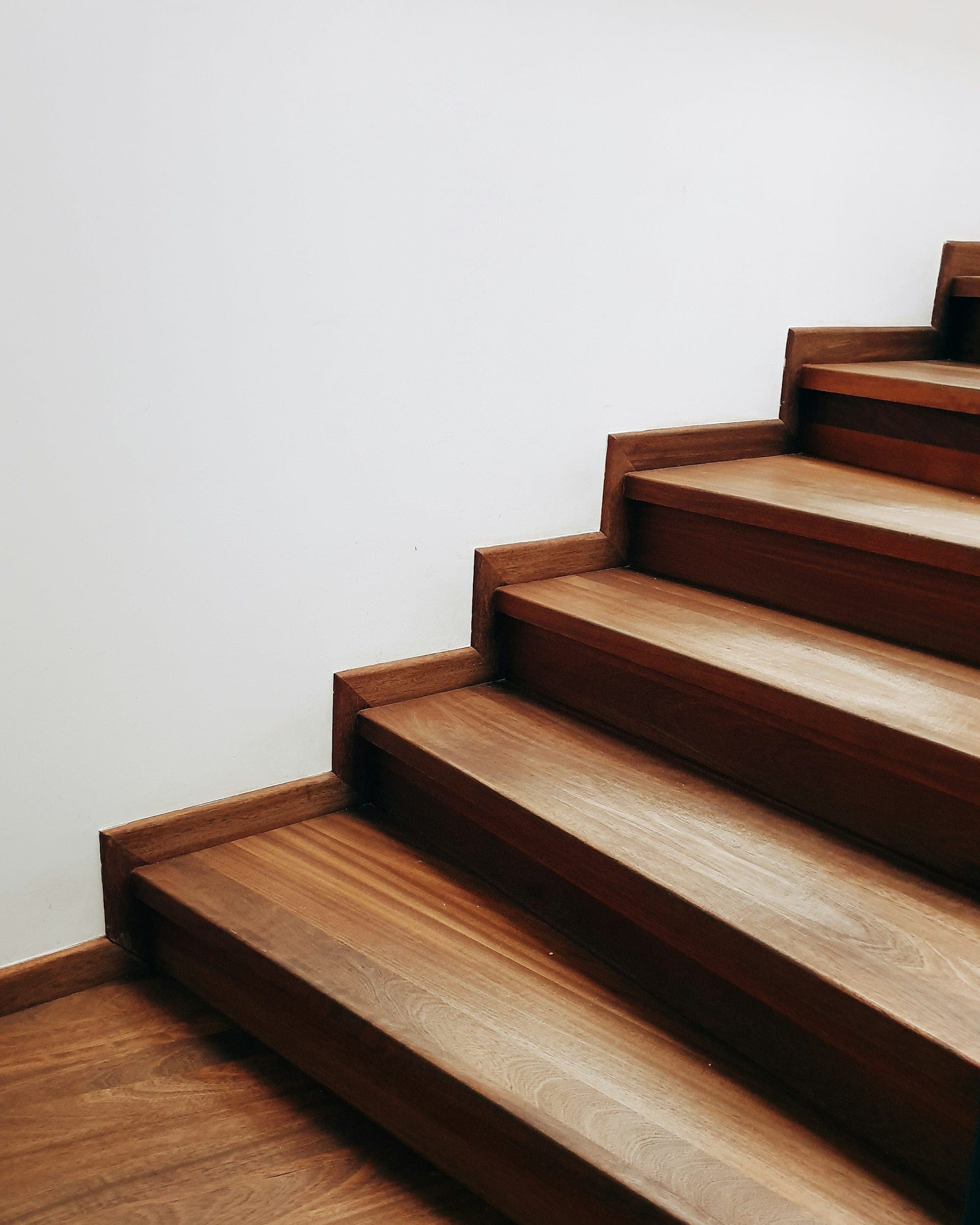 Close-up of stained wood stair treads and risers against a white wall