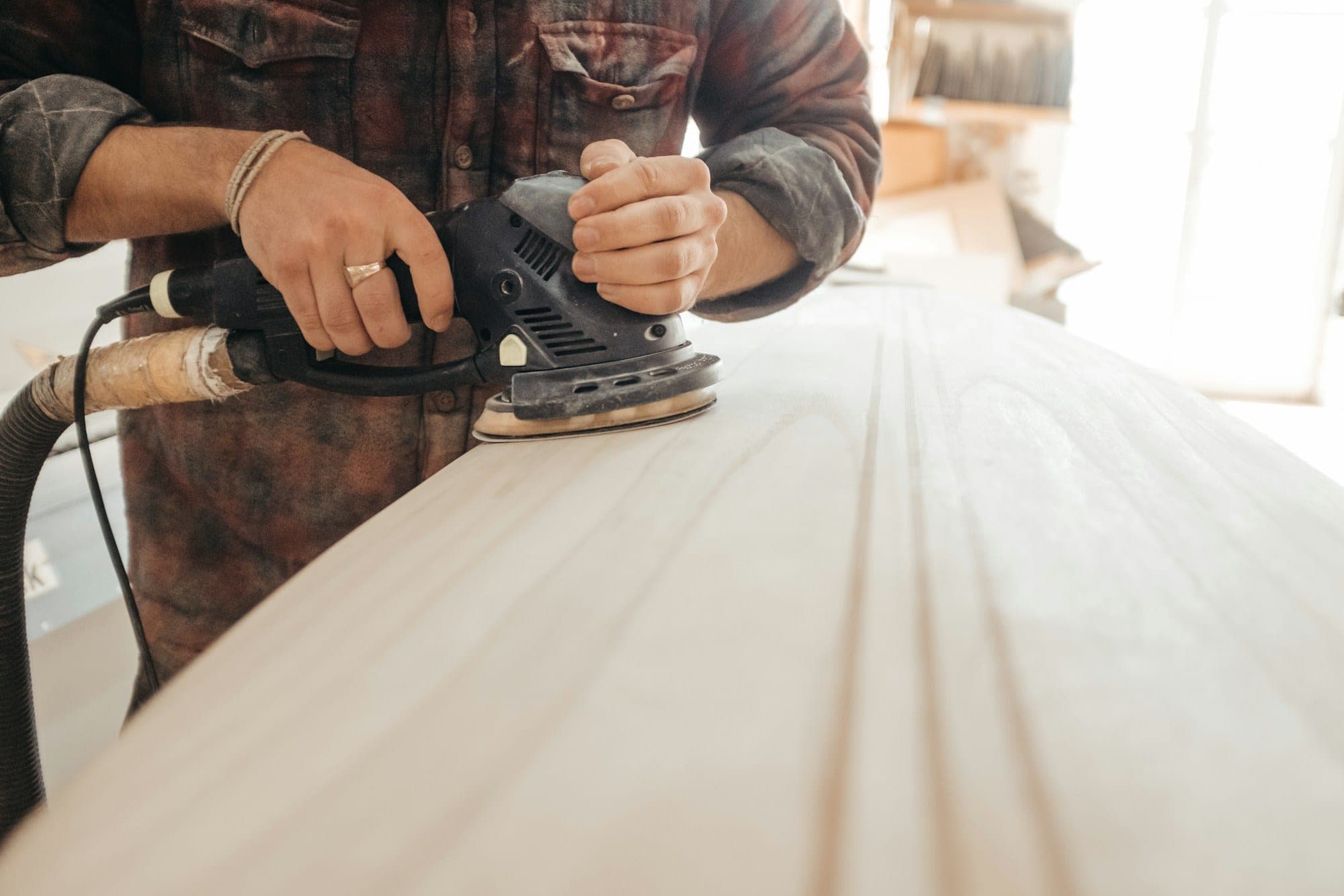 Woodworker sanding a light wood surface with an orbital sander