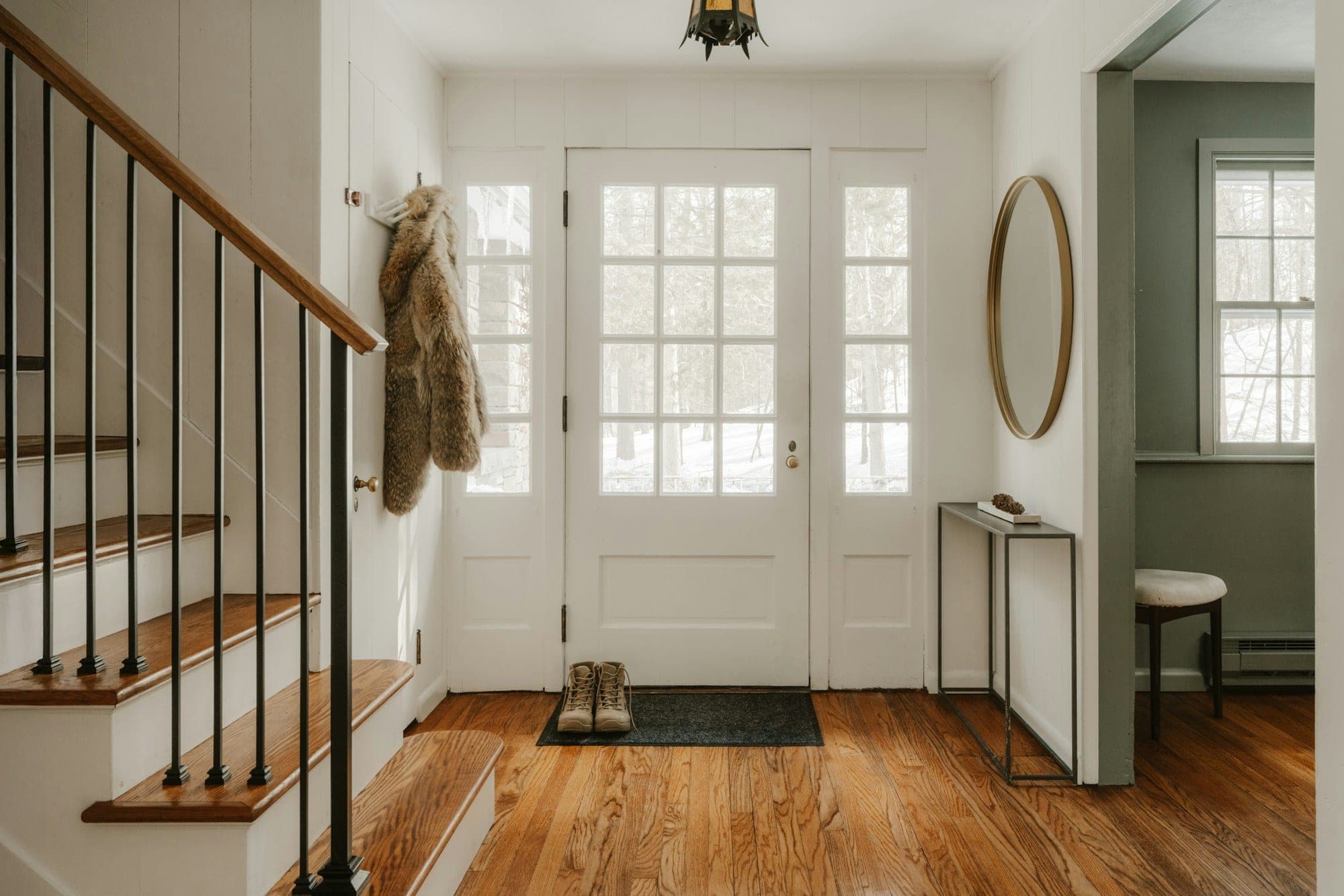 Entryway with a white glass-paneled door, wood stair treads and a painted railing