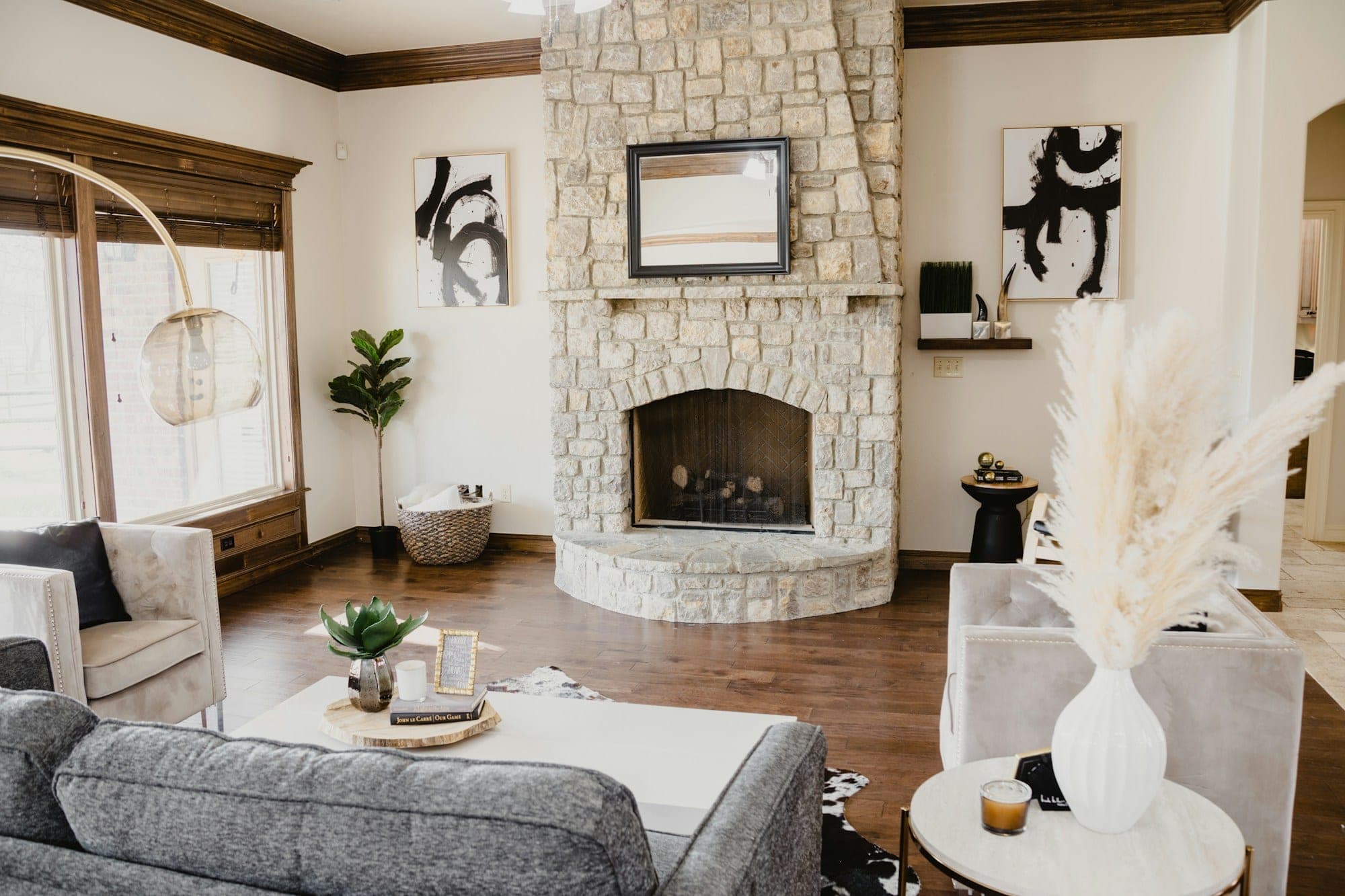 Living room with a stone fireplace, dark wood ceiling trim and hardwood floors