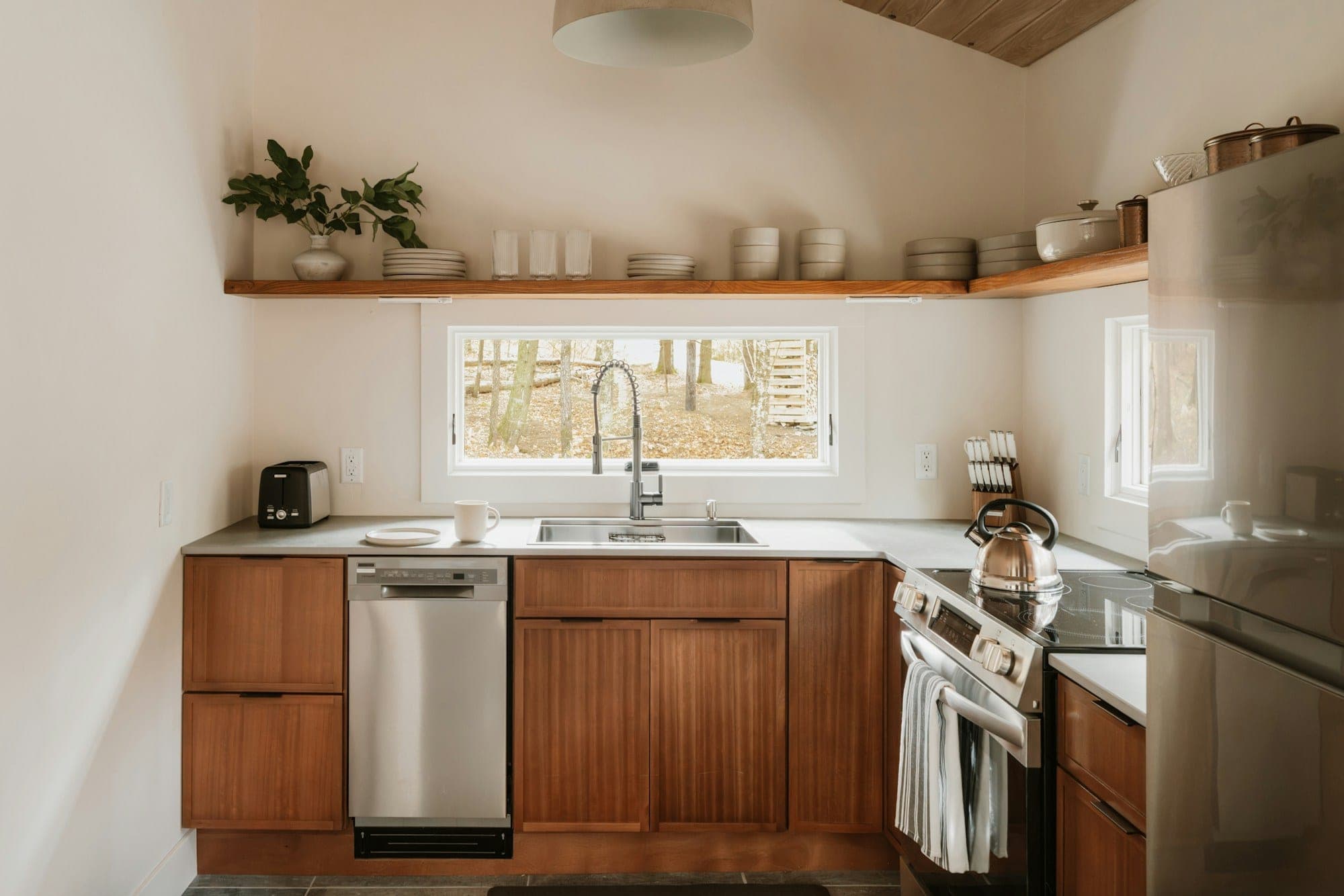Kitchen with walnut base cabinets, open wood shelving above the window and stainless appliances